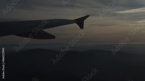 Airplane Wing Silhouette Over Mountains at Quiet Twilight