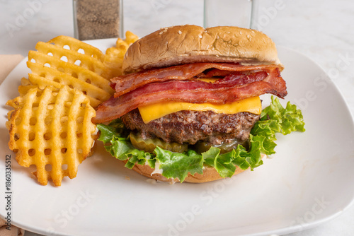 cheese burger top with bacon served with  waffle fries