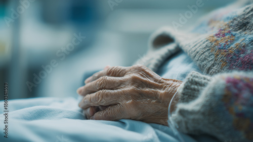 Close-up of a senior person's fragile hands resting gently on a light blue sheet in a hospital bed, symbolizing aging, healthcare, and patient care