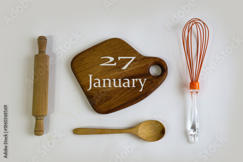 Calendar for January 27: numbers 27, name of the month January in English on a wooden cutting board