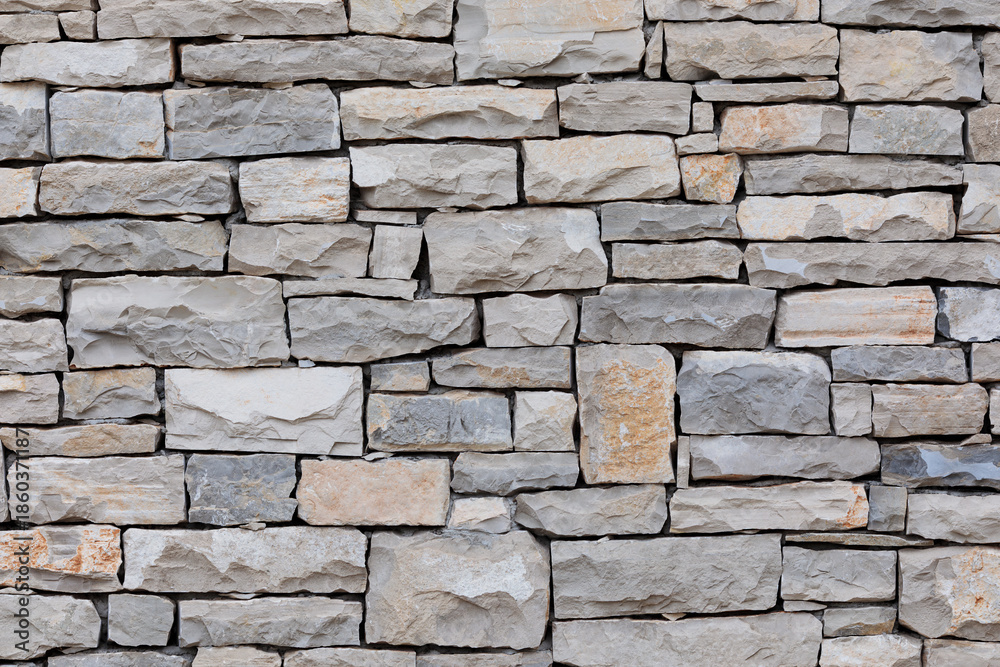 Fototapeta premium Rough cut light gray and beige stacked stone wall texture