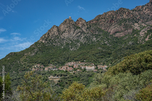 panoramic view village mountainous landscape towards the Gulf of Porto in sunlight with blue skies and spectacular cloud