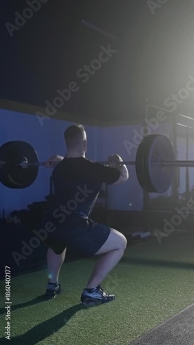 Man exercise deadlift with over head press weightlifting under spotlight in gym