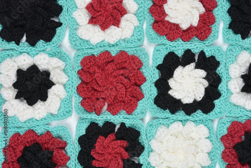 A collection of colorful crochet granny squares in black white and red with mint borders arranged for a blanket