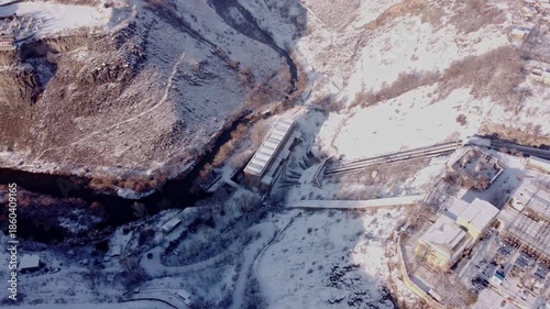 Aerial view of a large hydro electric power station in the mountains during winter. 