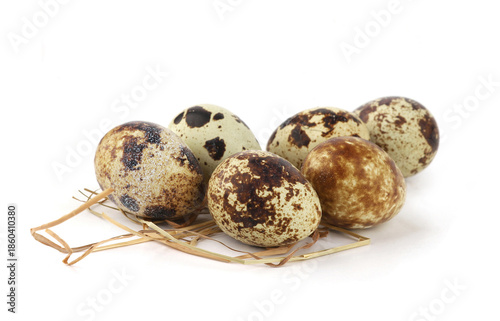 Quail eggs on straw isolated on white background. Natural patterned farm quail eggs in hay.