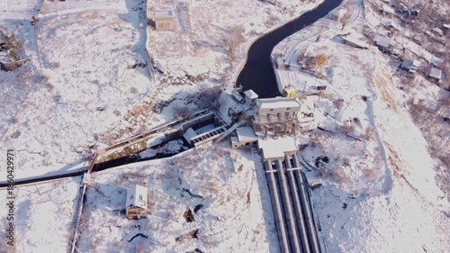 Aerial view of a hydro electric power station and reservoir in the mountains during winter