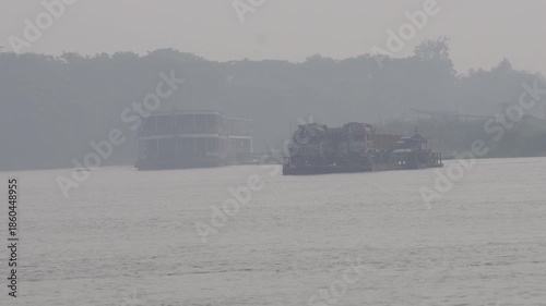 large hovercraft or air-cushion vehicle, moving across a body of water in hazy conditions