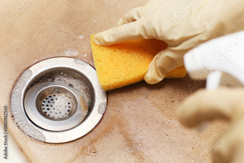 Fotografija Cleaning kitchen sink drain with yellow sponge
