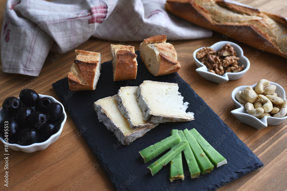 Fototapeta premium Aperitif with cheese bread olives and nuts on wooden table