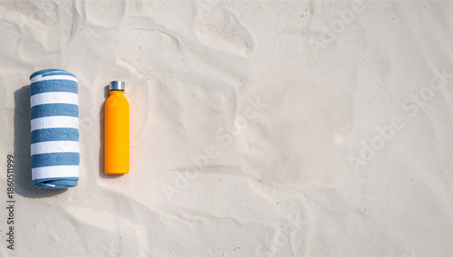 Protetor solar e toalha de praia listrada sobre areia clara em conceito de verão