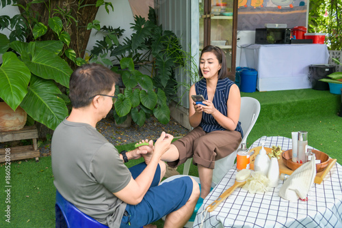 A heartwarming lifestyle series of a middle-aged Asian couple enjoying a relaxing home spa session. The man is seen lovingly caring for his wife by giving her a hand and foot massage