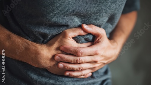 Man clutching his abdomen in severe stomach pain, suggesting cramps and digestive distress.
