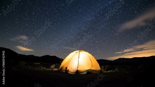 A serene camping scene at night with a glowing tent under a starry sky