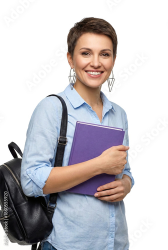 Woman stands isolated with a purple book and a black backpack in a bright space.