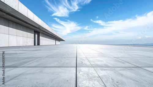 Empty, modern architectural facade with a vast, tiled floor and a blue, cloudy sky