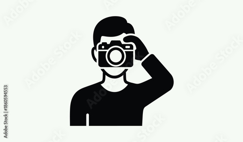 A simple black silhouette of a person using a camera to take a photo