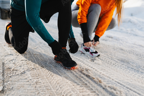 Foto Close-up of two runners tying shoelaces on sneakers before a winter run in the snow