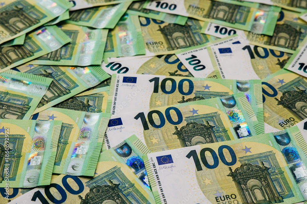 Obraz premium Stacks of hundred euro banknotes are spread across a flat surface, showcasing vibrant colors and intricate designs, symbolizing wealth and financial transactions