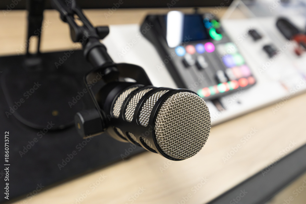 Obraz premium Podcast recording workspace with professional condenser microphone on adjustable stand and digital audio mixer with illuminated controls on a modern desk setup