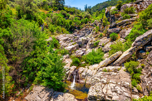 Waterfall spring from cliff mountains rocks on Ikaria island, Greece in summer with nature landscape view at longevity blue zone