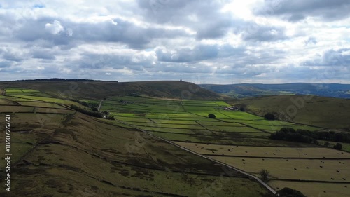 Aerial view of the landscape at Erringdon Grange near Hebden Bridge showing meadows with cows and sheep grazing and Stoodley Pike Moor and monument in the distance