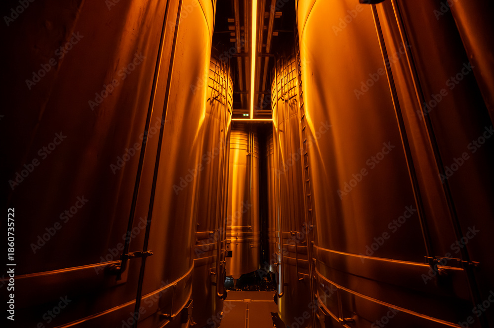 Naklejka premium Visit of modern underground caves with steel tanks for fermentation and oak barrels for aging og wine, traditional method making champagne sparkling wine in Reims, Champagne, France