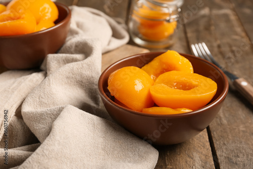 Bowls with sweet canned peaches on wooden background, closeup © Pixel-Shot