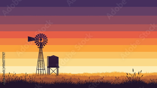 Rural windmill at sunset with grass and water tank