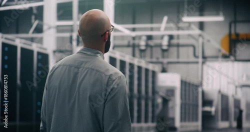 IT Specialist Conducting Physical Server Hall Inspection. Professional Engineer Walks Purposefully Through Massive Data Center Hall, Conducting Visual and Physical Inspection of Infrastructure Scale.