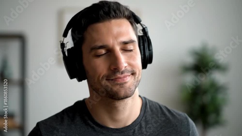Relaxed man with eyes closed enjoying music through headphones at home