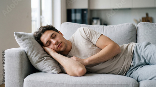 A man takes a peaceful nap on a comfortable couch in a living room, embodying tranquility and relaxation.
