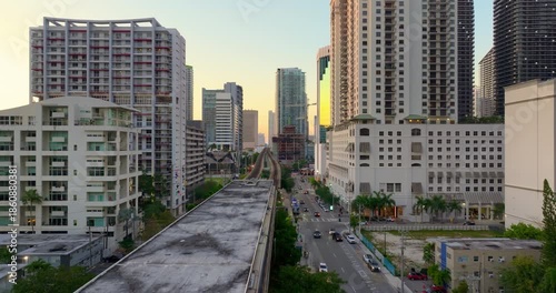 View from above of public train passing through downtown railroad of Miami, Florida, USA. Financial district skyscrapers at sunset
