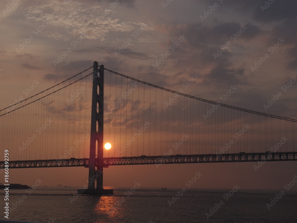 Obraz premium 夕日に照らされた大きな吊り橋と海の風景