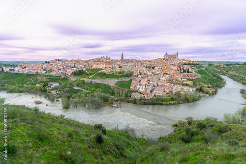 Scenic aerial view of Toledo Spain during spring twilight. The Rio Tajo river winds around the historic city center as a grand natural barrier.