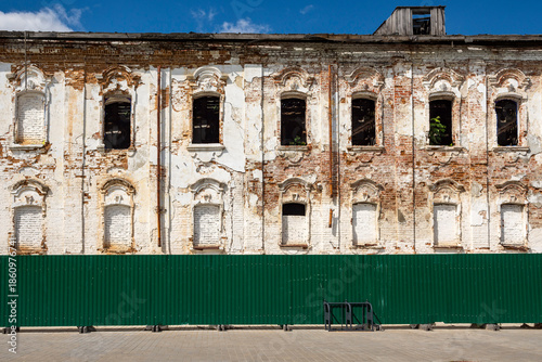 The weathered facade of an old building, with its brickwork and window openings still intact, is a sunny autumn day.