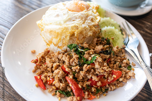 Tableau sur toile Spicy Thai basil stir-fried with minced beef and crispy fried egg on top of steamed rice, authentic Pad Kra Pao beef served with chili and garlic, popular Thai street food concept
