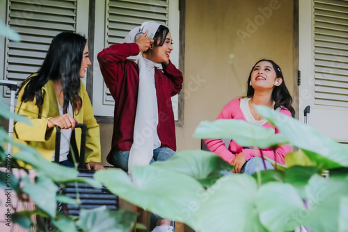 Three vibrant women are joyfully reunited, ready for a memorable journey together. With their luggage in tow, these friends exude happiness and anticipation, poised to explore new horizons.
