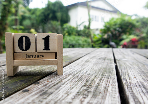 Wooden cube calendar for 1st January place on an old table in a sunny garden background