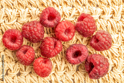 Red ripe raspberries isolated on a straw mat, top view, macro.