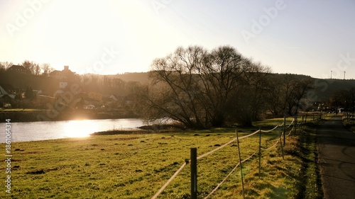 Golden Hour Riverside Landscape with Castle Silhouette and Rural Idyllic Atmosphere