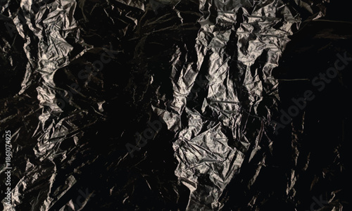 Abstract dark background texture of crumpled black plastic material creates dramatic shadow and light effect
