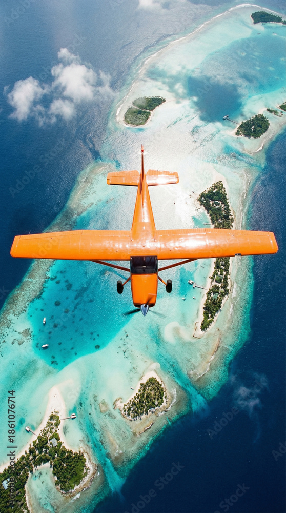 Naklejka premium Top-down aerial of an orange bush plane flying over tropical lagoons