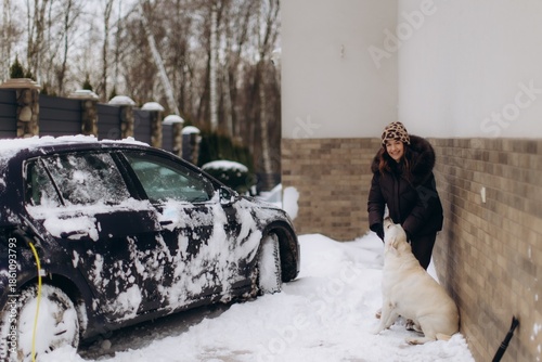 Woman charging electric car with dog in winter snow