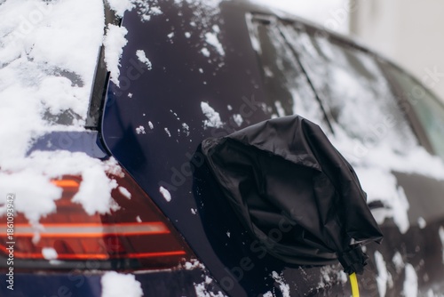 Electric car charging in winter snow with connector cover