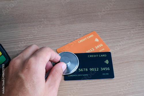 Healthcare cashless payment concept with a stethoscope placed on credit cards near an EDC terminal on a wooden desk. Perfect for healthcare, insurance, fintech, hospital, billing, and medical payment