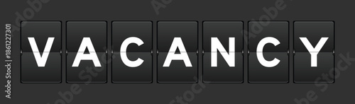 Black color analog flip board with word vacancy on gray background