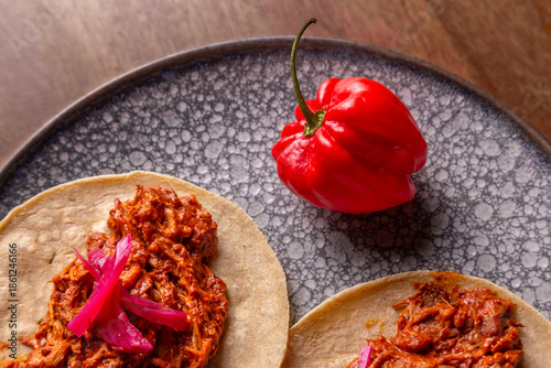 Taco de cochinita con tortilla de maíz, sobre mesa de madera 