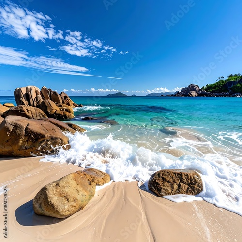 Tropical beach with turquoise water, golden sand, and rock formations under a blue sky with scattered clouds