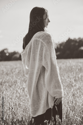 Woman in oversized sweater standing in rye field during soft daylight